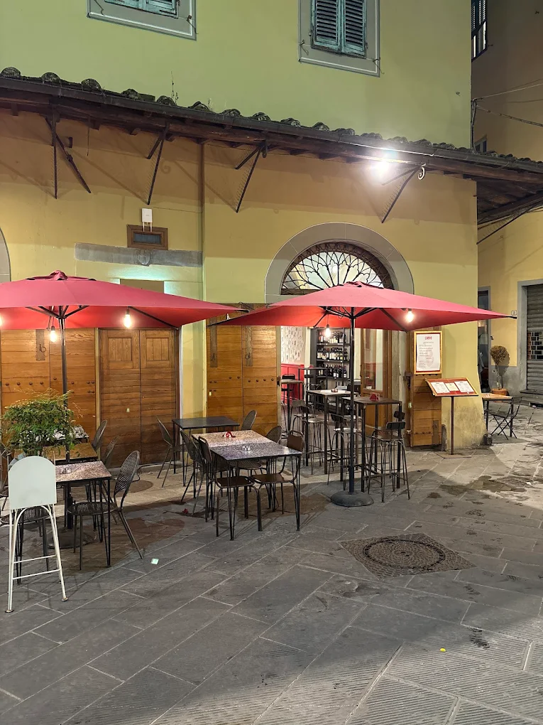 Dehors esterno di Coèvo la sera, tavoli sotto gli ombrelloni rossi nella piazza