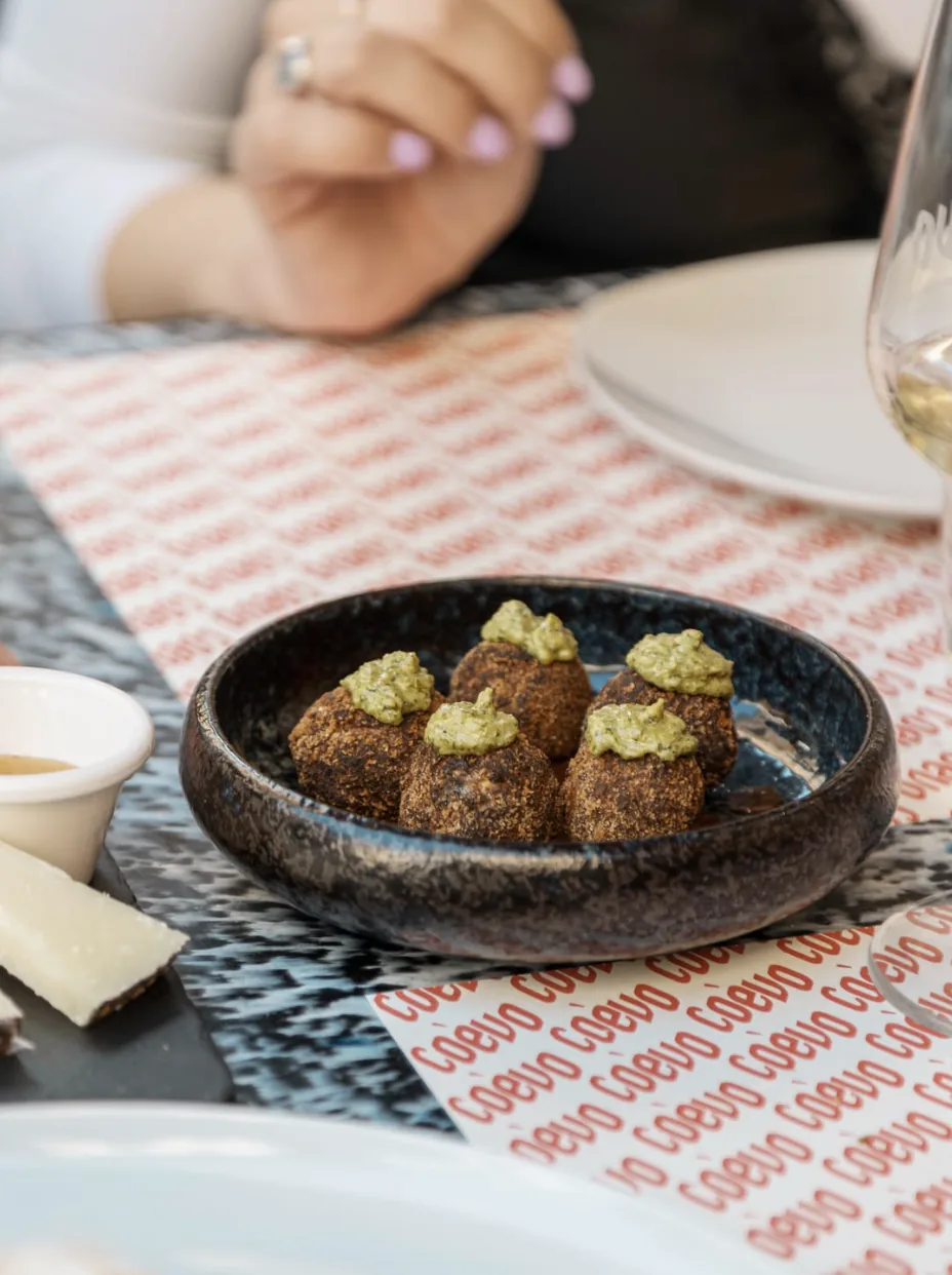 Polpette fritte con crema al pesto servite in ciotola di ceramica scura