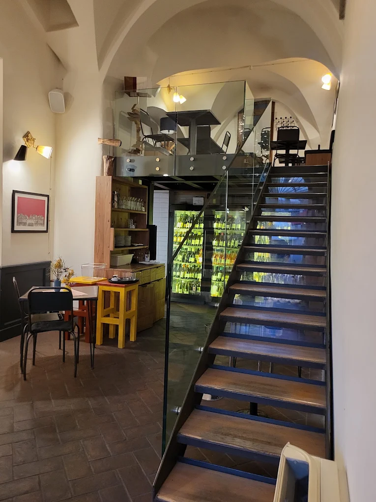 Sala interna di Coèvo con volte a crociera, scala in ferro e cantina vini a vista