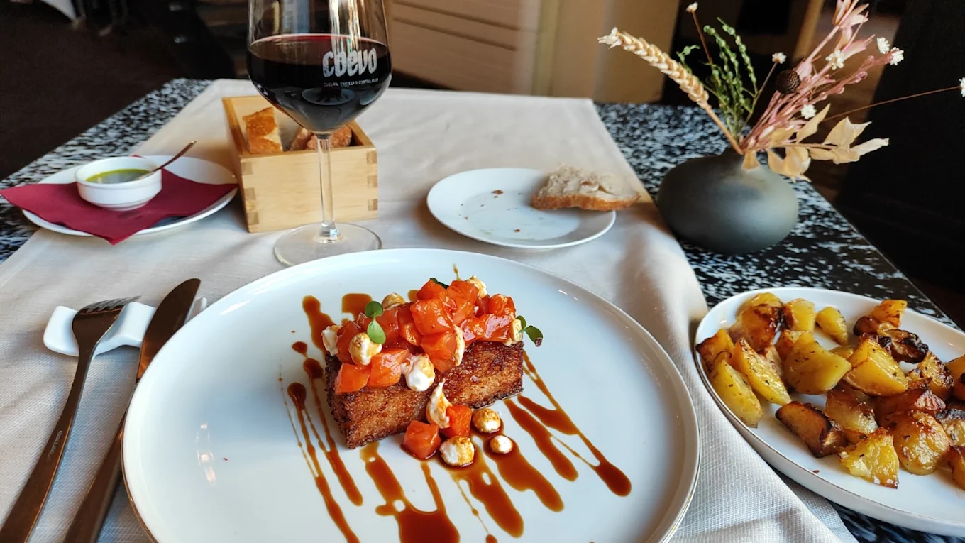 Tavola apparecchiata da Coèvo con calice di vino rosso brandizzato e portata principale