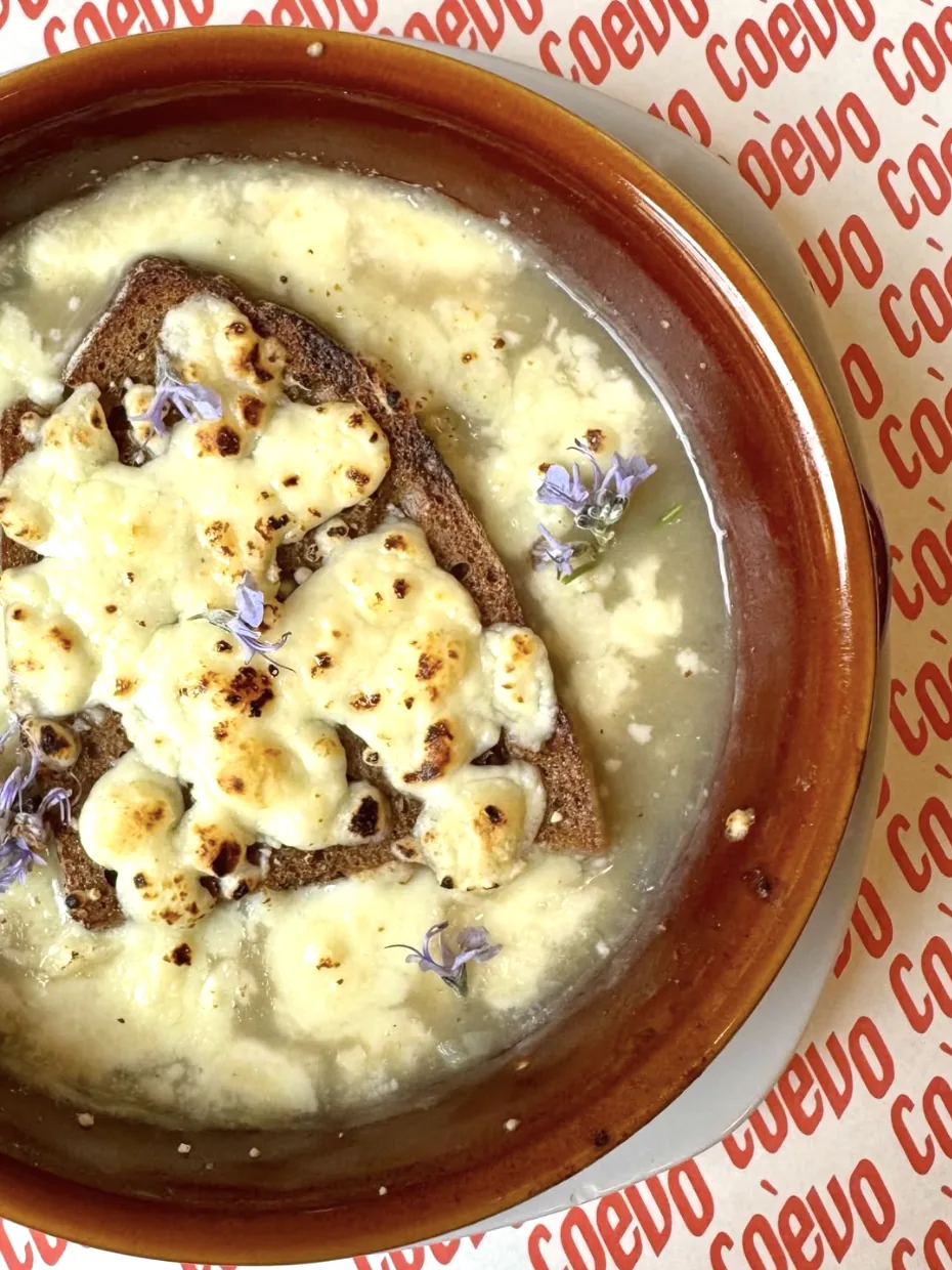 Zuppa di cipolle gratinata al formaggio con crostone di pane e fiori di rosmarino